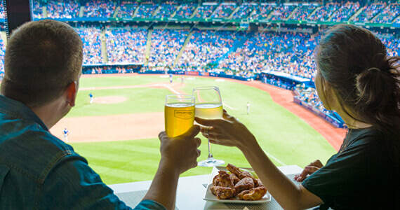 A couple enjoying a meal while watching a live sports game, which you can do at one of the most unique restaurants in Toronto!