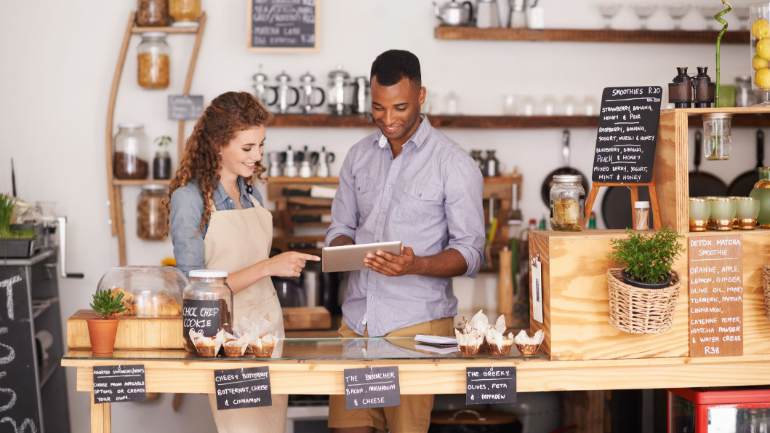 A restaurant manager and employee on a tablet behind the counter