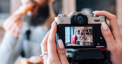 Someone taking a photo of a man eating pizza in their restaurant.