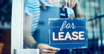 Restaurant owner taking down a for lease sign at the front door or restaurant