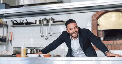 restaurateur smiling in front of woodfire oven