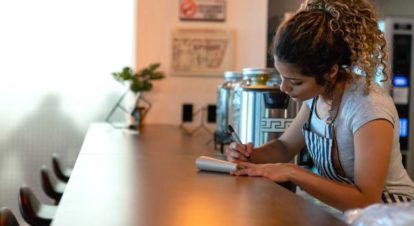 cafe owner reworking the menu with a pen and paper