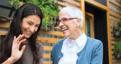 Mother and daughter laughing on a restaurant patio