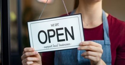 Restaurant owner flipping over we are open sign at front door