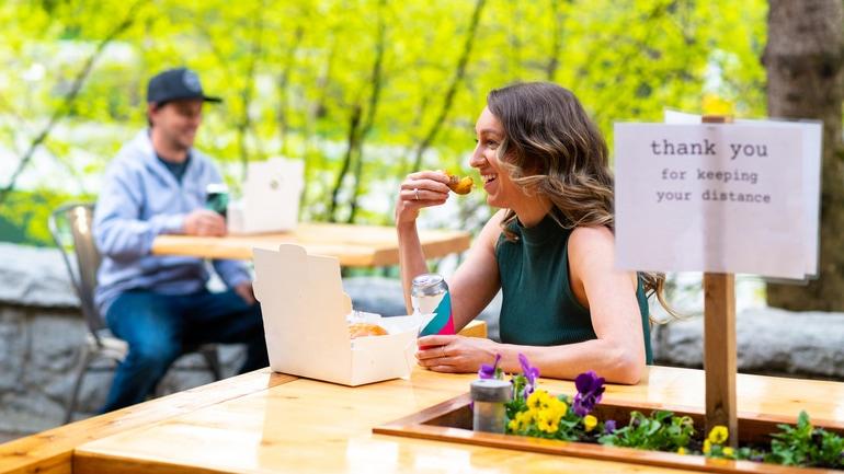 Woman and a man dining outside at separate tables