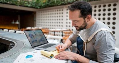 Restaurant owner working on laptop and financial paperwork