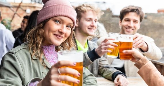 Group of friends raising their beers on the outside patio