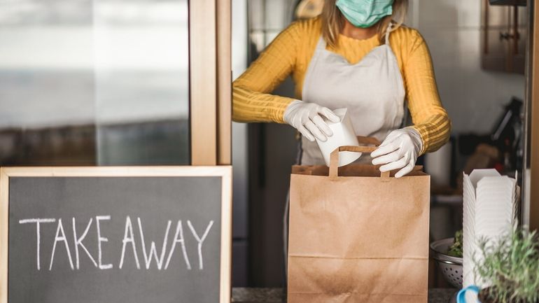 A woman packing a bag of food for takeout