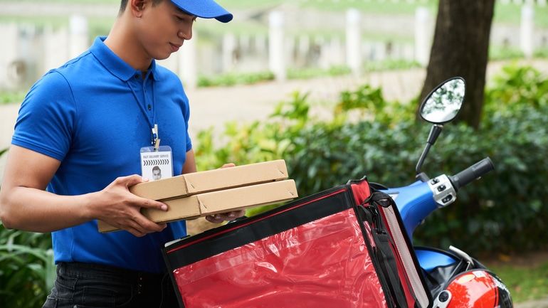 Delivery driver packing takeaway boxes on scooter