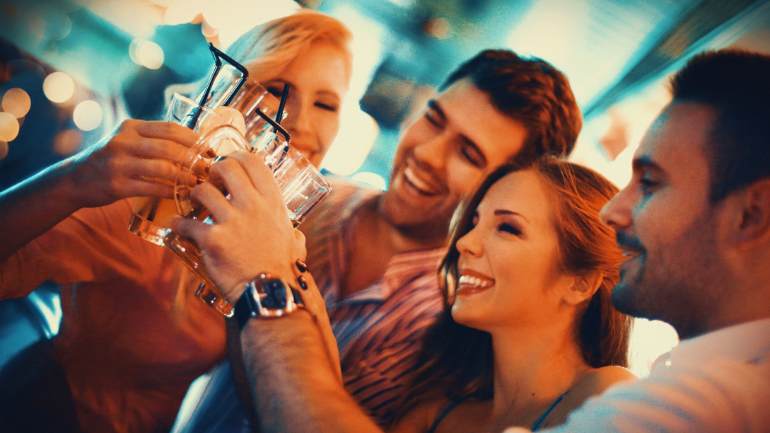 A group of friends smiling and raising a toast with their glasses.