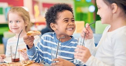 Three children having fun eating pizza