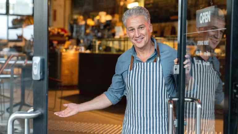 staff member welcoming you into open restaurant door