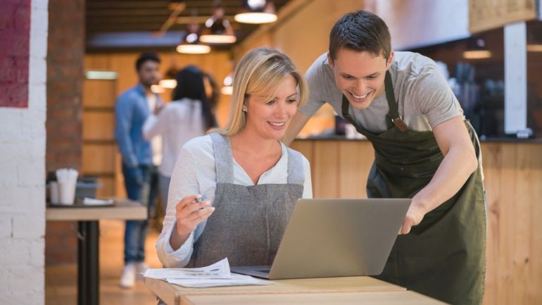 Restaurant employees working together on a laptop