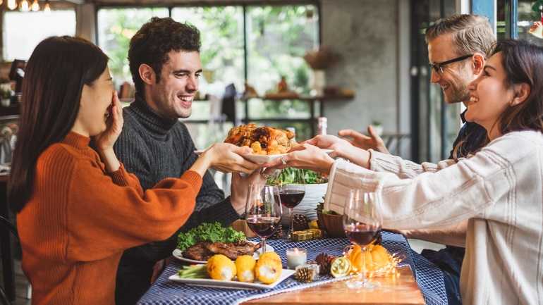 Diners passing family style plates at a restaurant table