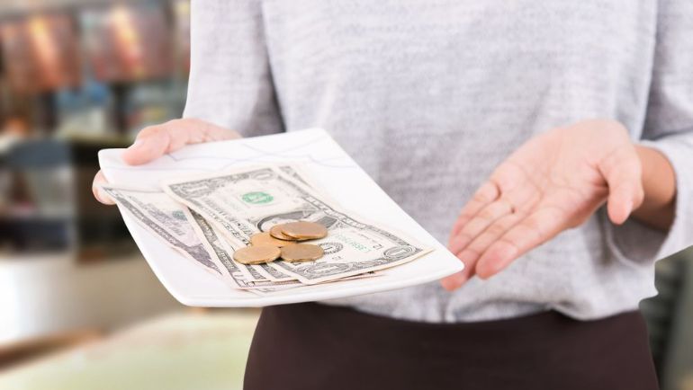 Server holding bills and coin on a small tray