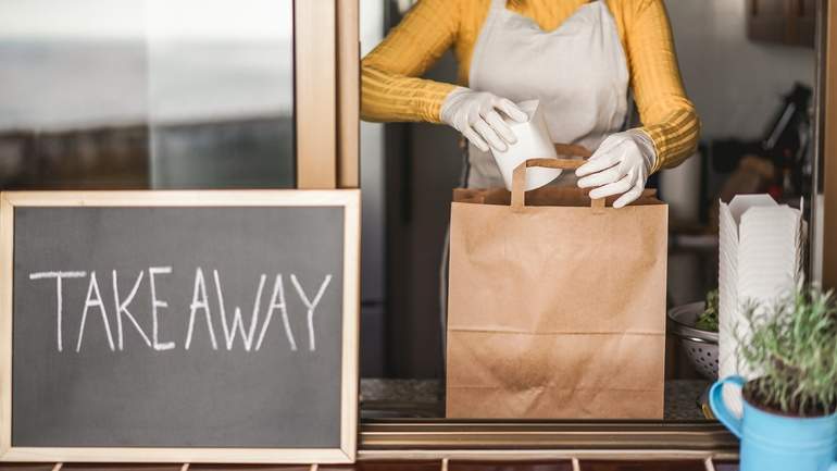 Employee packing a bag of food at a take away window