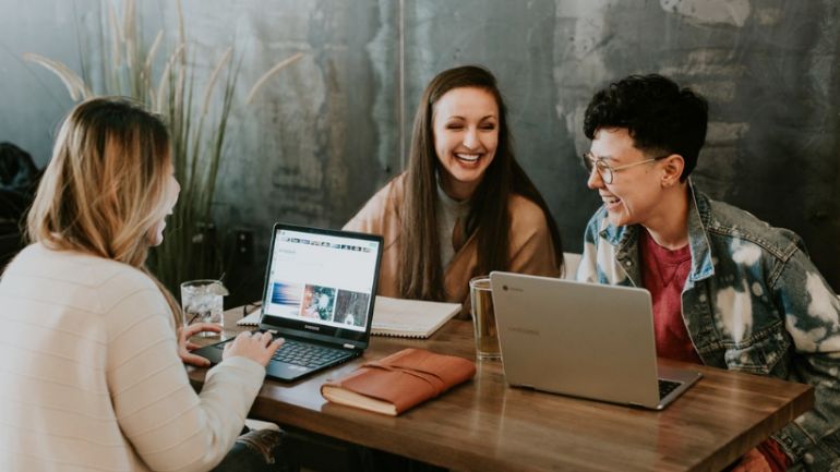 three customers at a cafe table using wifi on their laptops