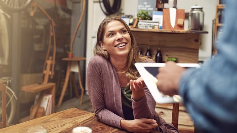 A waiter using a restaurant iPad POS system to take a woman's order