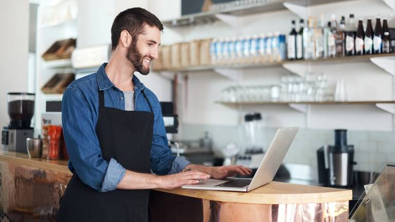 cafe owner updating social media posts on laptop