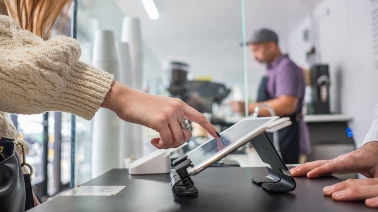 customer using self-serve kiosk at cafe counter