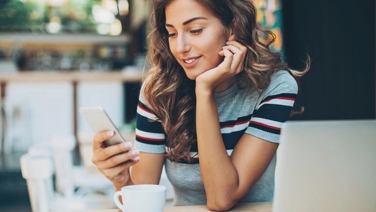 Woman using a smartphone to access a restaurant app in a cafe.