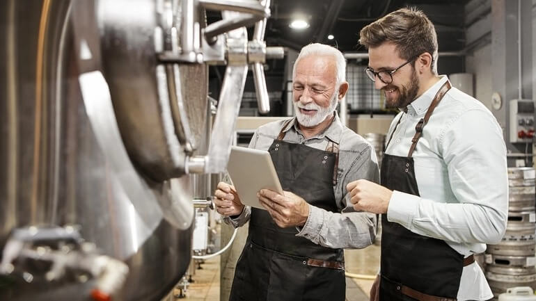 Two men using an iPad inside a brewery.