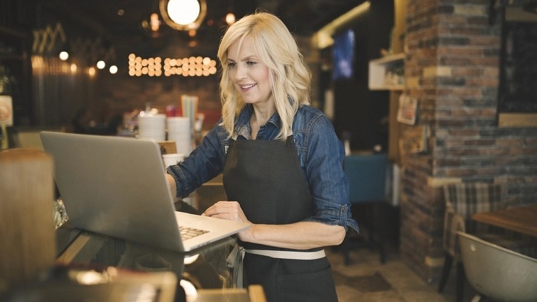 women works on a computer at a restaurant.