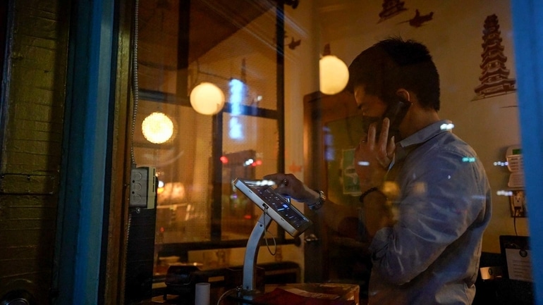 DaiLo restaurant General Manager Trevor Chen using a TouchBistro POS while talking on the phone.