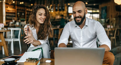 Woman and man using a laptop in a restaurant.