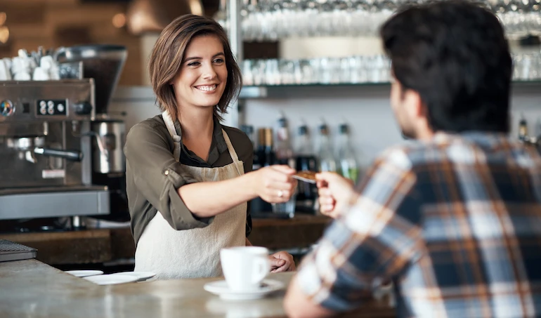 Shot of a cheerful female bartender receiving a card as payment from a customer inside of a restaurant