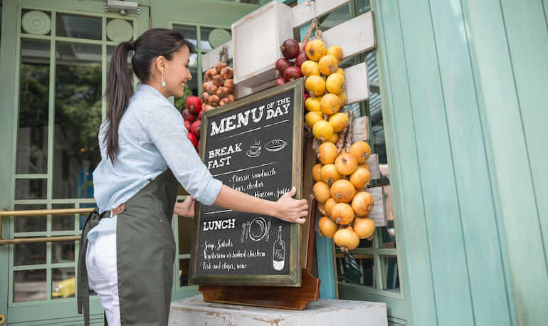 Happy restaurant manager hanging the menu at the entrance - new business concepts