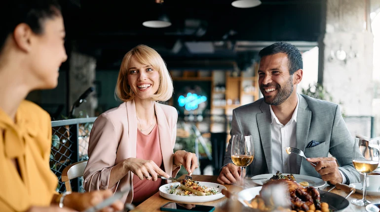 Group of happy entrepreneurs communicating while enjoying in business lunch in a restaurant.