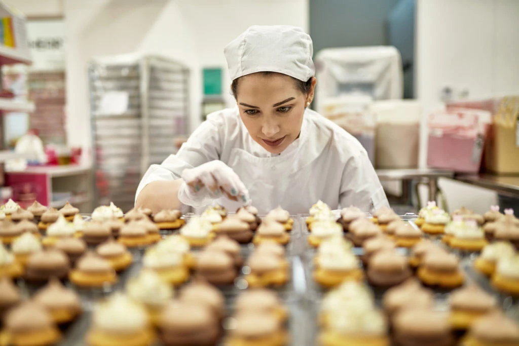 A bakery decorating dozens of vegan cupcakes for a catering job.