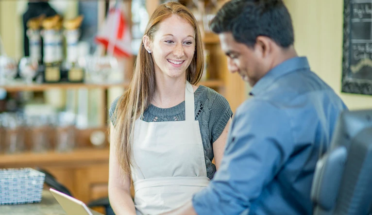 A restaurant owner is training a new employee at his local cafe and small business.