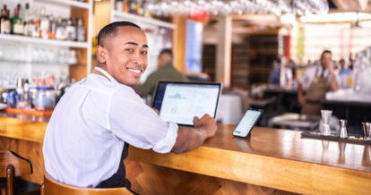 Portrait of a small business owner working using laptop at a bar.