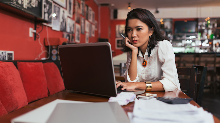 Woman sitting in a restaurant on her laptop.