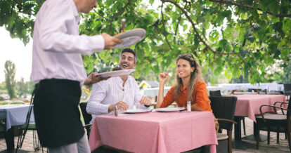 A couple being served by a server at a restaurant.