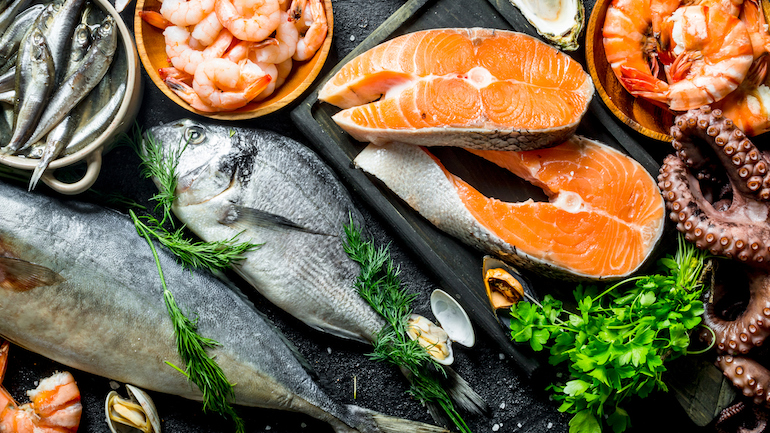 Display of fresh salmon steak with a variety of other seafood and herbs.