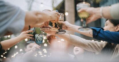 A group of friends toasting their glasses in celebration at an outdoor patio.