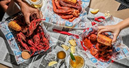 Three trays of red crawfish on a table.